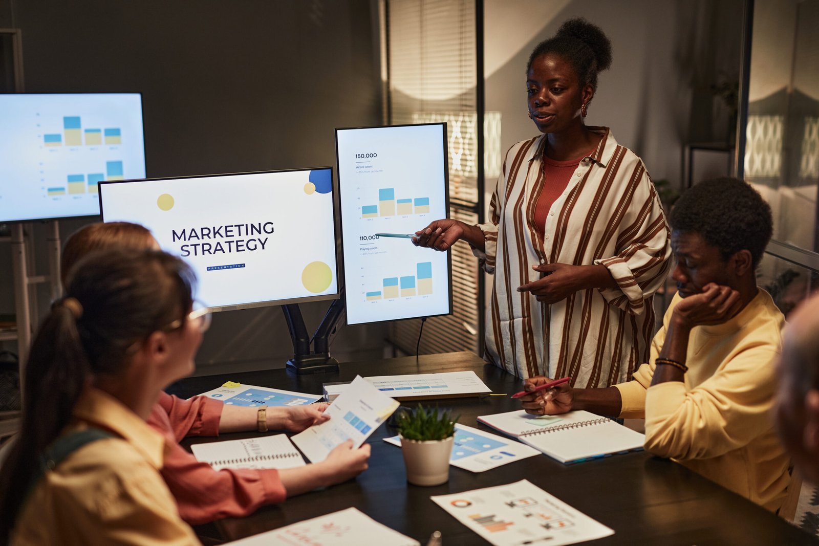 Black Woman Presenting Plan At Meeting - Home Builder Marketers